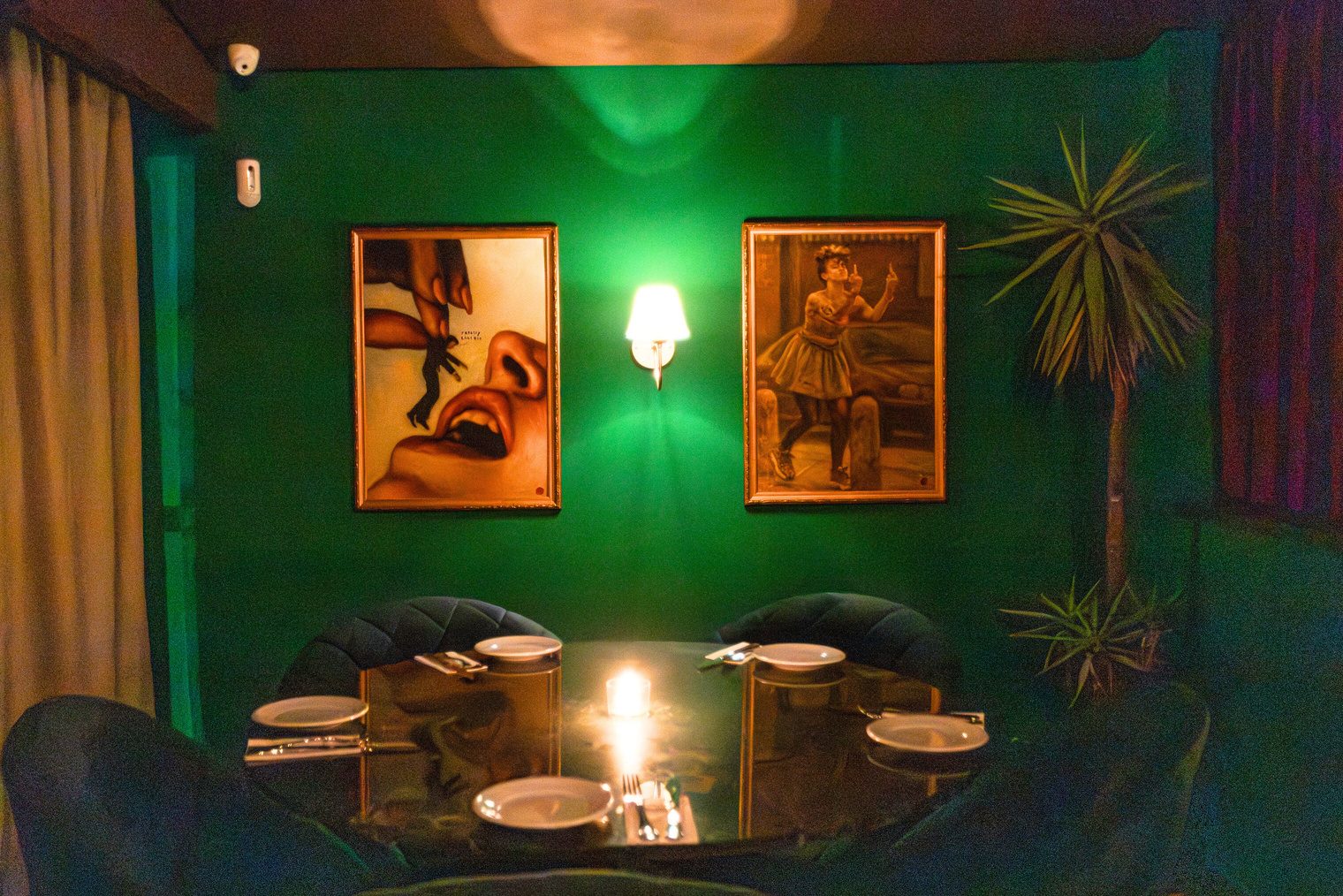 Parede verde do Coxixo com quadros e arandela acesa